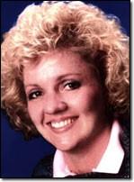 Woman with curly blonde hair smiles broadly at camera